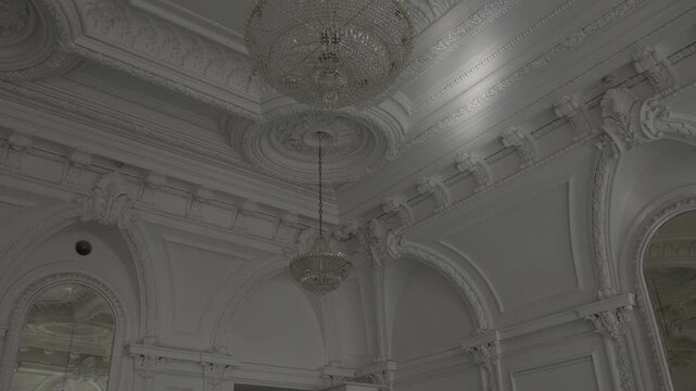 Ornate classical reception hall ceiling with suspended crystal chandeliers and sculpted plaster medallion, with ceiling, chandelier, plaster, medallion detail, showing molding, cornice, arch