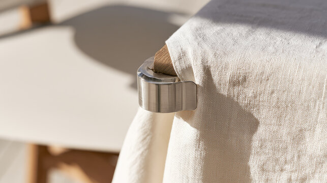 Tablecloth clamp holding cotton fabric on oak tabletop corner in soft outdoor sunlight with neutral background and generous negative space