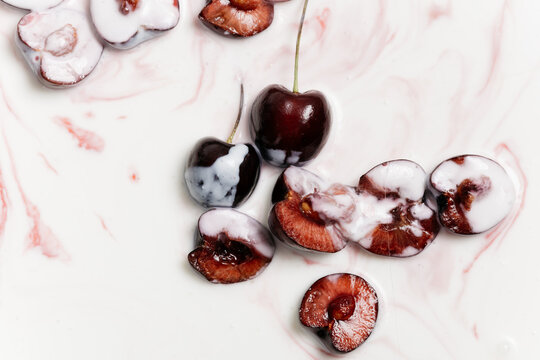 A juicy and ripe cherry berry with a stone floats in a milk drink. Concept: desktop wallpaper or greeting card with a creative image of berries from a farm plot. creative macro photography