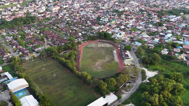 Aerial perspective of a sports field and track located in a residential area of South Kalimantan