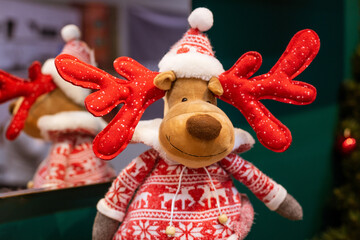 Plush reindeer toy with red antlers in a knitted nordic sweater and pompom hat, ideal for christmas gift shop, soft toy retail and holiday decor content. © Екатерина Переславце
