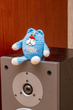 A knitted cat stands on a speaker.
