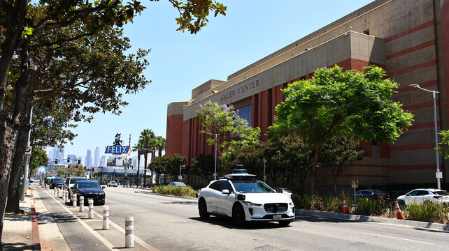 Los Angeles, California &ndash; July 28, 2026: Waymo autonomous robotaxi driving past the Galen Center and Historic Chevrolet dealership with iconic Felix the Cat sign in the background