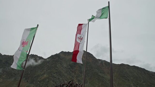 flags fluttering in the wind on Scenic panorama of the Tyrol Alps in Austria with dramatic rocky peaks towering mountain ridges and pristine wilderness creating an inspiring European travel des
