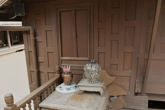 rustic still life featuring traditional patterned ceramic vases on a timber stand against the dark wooden paneled wall of an oriental heritage house