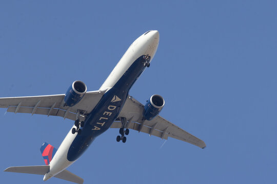 Delta air lines jet flying in blue sky with landing gear down