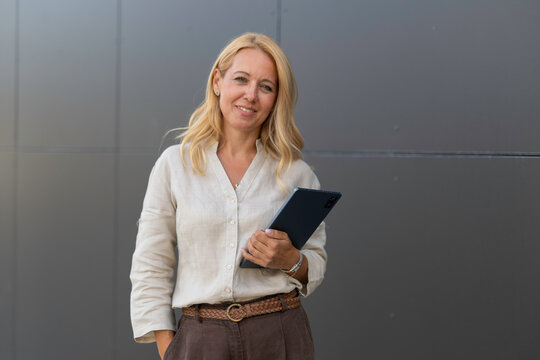 Confident business woman holding digital tablet outdoor