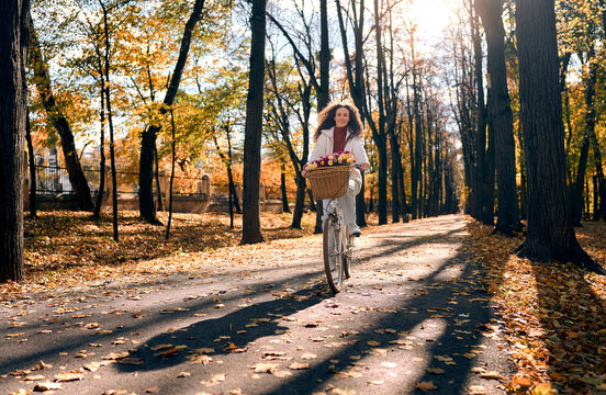 Woman cycling through a sunlit autumn park.