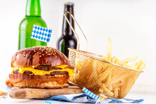 Oktoberfest Burger menu with french fries, pretzels, beer bottles. Tasty cheese hamburger in pretzel bun, with french fries, bavarian beer snacks, with checkered tablecloth and Oktoberfest decor