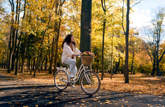 Woman cycling through an autumn park.