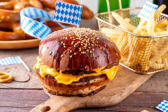 Oktoberfest Burger menu with french fries, pretzels, beer bottles. Tasty cheese hamburger in pretzel bun, with french fries, bavarian beer snacks, with checkered tablecloth and Oktoberfest decor