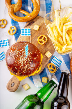Oktoberfest Burger menu with french fries, pretzels, beer bottles. Tasty cheese hamburger in pretzel bun, with french fries, bavarian beer snacks, with checkered tablecloth and Oktoberfest decor