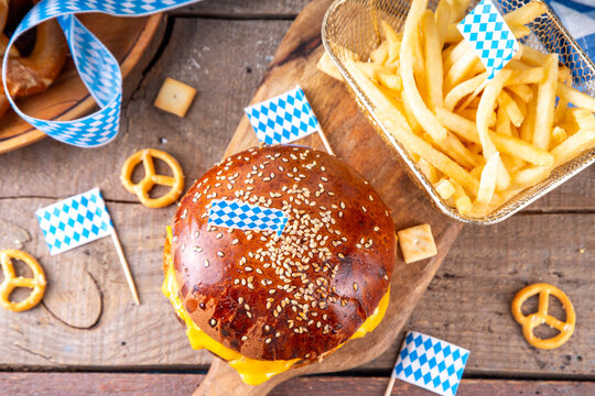 Oktoberfest Burger menu with french fries, pretzels, beer bottles. Tasty cheese hamburger in pretzel bun, with french fries, bavarian beer snacks, with checkered tablecloth and Oktoberfest decor