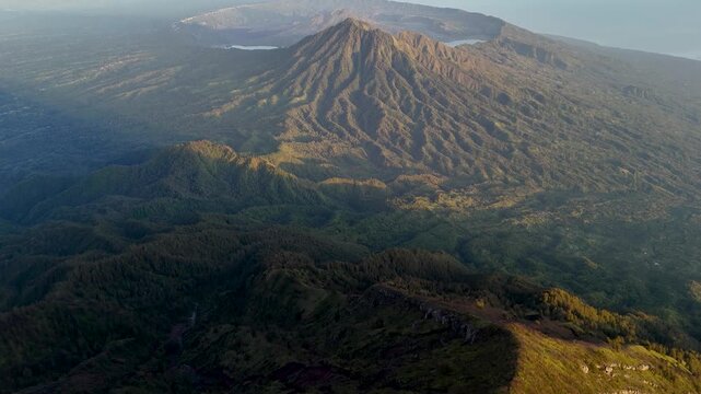 Aerial view of Mount Agung ridge showing volcanic terrain and rocky slopes illuminated by golden morning light Rendang, Bali, Indonesia.