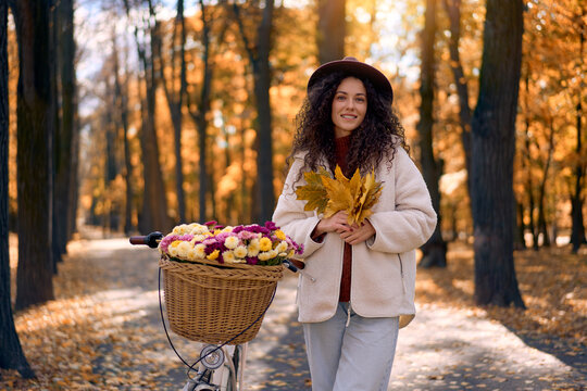 Woman with flower bicycle in an autumn forest.