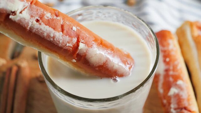 Close-up view of sweet fartons pastry dipped into a glass of refreshing horchata (orxata), traditional Valencian tiger nut milk drink.