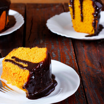 Brazilian carrot cake with chocolate frosting, served on a white plate with slices in the background.