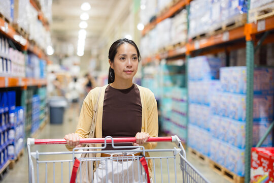 Woman pushing shopping cart inside large wholesale store