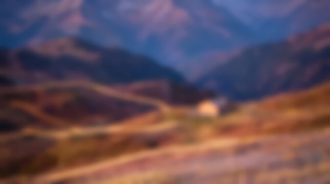 Mountain landscape blurred into soft abstract shapes and warm tones. This out of focus scenery captures the essence of rolling hills and distant peaks in a gentle, artistic composition.