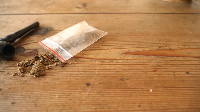 Marijuana and small pipe on table. Dolly reveal shot.