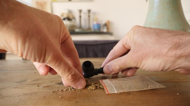 Close up of a small pipe being stuffed with marijuana. 