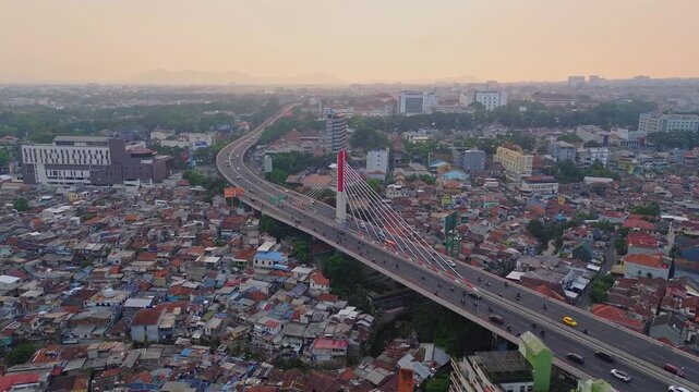 Aerial view of Pasupati Bridge with traffic flowing over the cable-stayed structure above the dense urban rooftops of Bandung, West Java, Indonesia.
