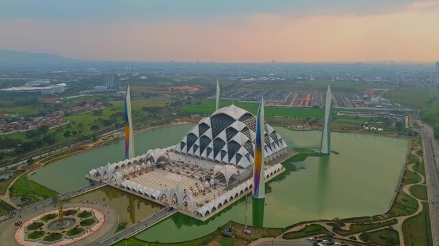 Aerial view of the modern Masjid Raya Al Jabbar mosque surrounded by a reflective lake and landscaped parkland in Bandung, Jawa Barat, Indonesia.