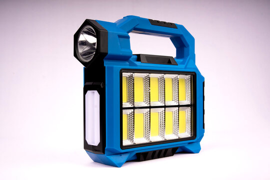 Multi-functional blue portable LED searchlight lantern showing front COB floodlight, top spotlight, side light bar, and ergonomic carrying handle.
