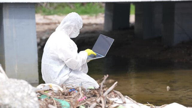 Environmental Scientist Protective Suit Laptop Computer Polluted Stream Under Bridge During Outdoor Water Quality Inspection and Water Pollution Environmental Research Survey
