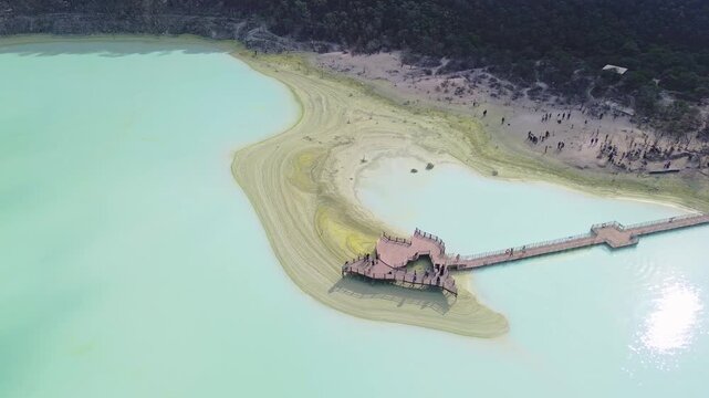 Aerial view of Kawah Putih Ciwidey with its turquoise volcanic lake, wooden pier, and surrounding forest in Bandung, West Java, Indonesia.