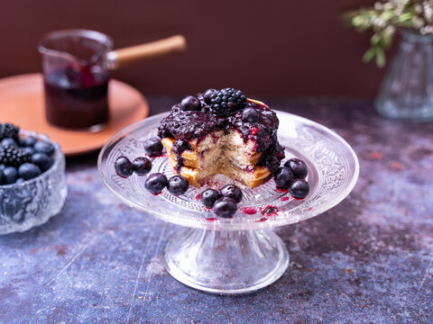 Berry Pancakes on Glass Cake Stand. Homemade pancakes topped with berry compote and fresh berries served on an elegant glass cake stand
