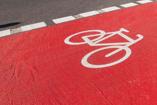 White bike sign on new red bicycle lane as sustainable city development with separated bikeway for safety in city traffic for bikers and cyclists. Sustainable transport by bike on new bike lane.