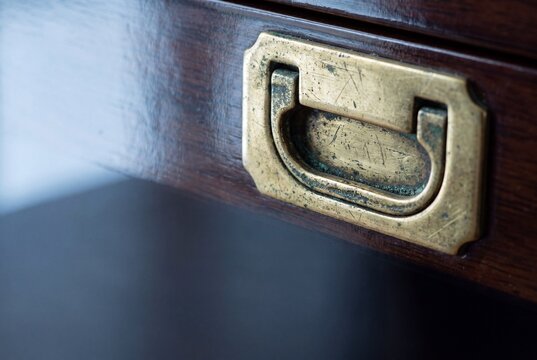 Aged brass hardware with green patina on a dark lacquered wooden surface