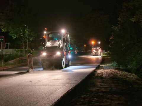 Nighttime road construction and asphalt resurfacing with heavy machinery