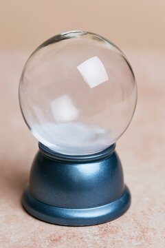 Empty glass snow globe with a smooth transparent sphere and metallic blue base, featuring a warm golden glow for a holiday mockup template
