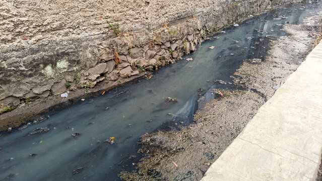 Polluted dirty water in an urban drainage ditch with garbage and waste