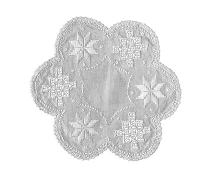Decorative white fabric doily with a four-lobed floral shape, embroidered geometric motifs, openwork cutwork details and textured edging, isolated on a transparent background.