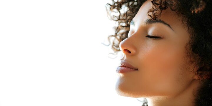 Serene young woman with curly hair resting peacefully with closed eyes against a white background.