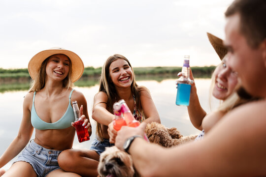 Friends Enjoy Drinks by the River During Summer Days and Share Laughs With Pets Close By