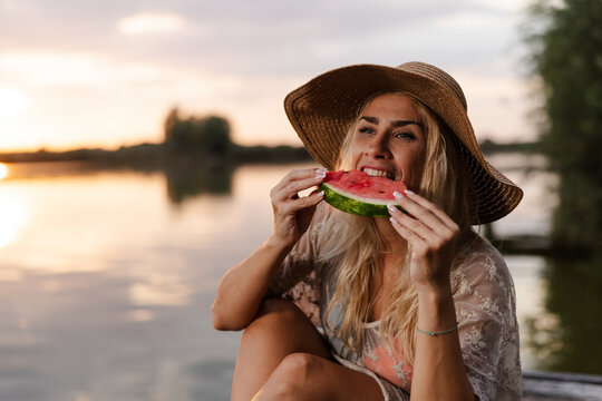 Woman Enjoys Watermelon by the River During Summer Evening