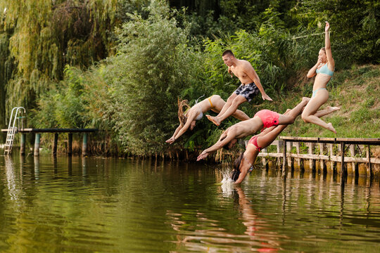 Friends Jump Into a River During Summer Fun Together in the Warm Sun