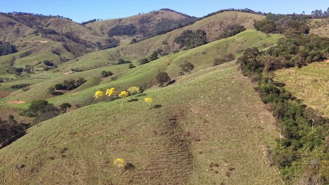 Aerial view of hills in Brazilian countryside under a blue sky.