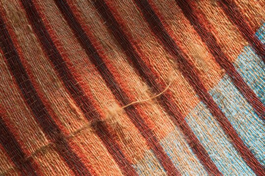 Woven cloth surface with red diagonal stripes and a blue accent, featuring tactile slubbed yarn and natural imperfections for fashion and textile backdrops