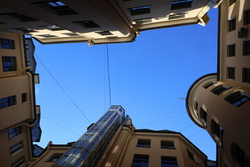 Courtyard well framed by beige apartment buildings with ornate cornices  dramatic upward perspective emphasizes verticality and contrast between dense architecture and vivid blue sky © Semiglass