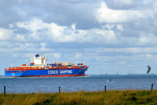 OTTERNDORF, DEUTSCHLAND &ndash; 10.08.2026: Das in  China registrierte Containerschiff XIN LIAN YUN GANG auf der Elbe in H&ouml;he OTTERNDORF. Im Vordergrund ein Kitesurfer auf der Elbe.