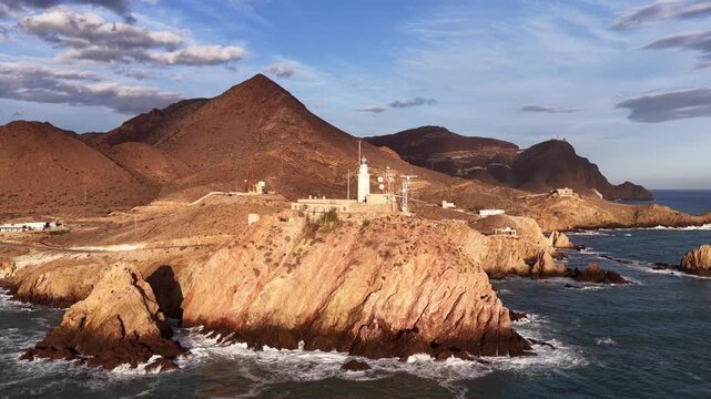 Aerial view of Faro de Cabo de Gata lighthouse perched on rocky cliffs overlooking the Mediterranean Sea in San Jose, Andalucia, Spain.