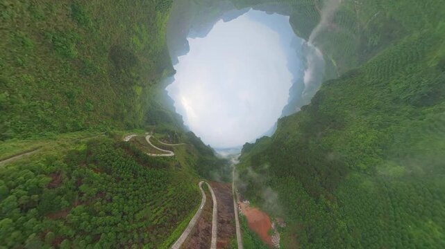 Drone view tunnel effect landscape of green mountains, agriculture field, zigzag road in Fengtang village, Hechi, Guangxi, China, 4k real time footage travel concept b roll shot.