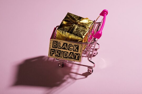 Black Friday Gift Box in Mini Shopping Cart on Pink Background