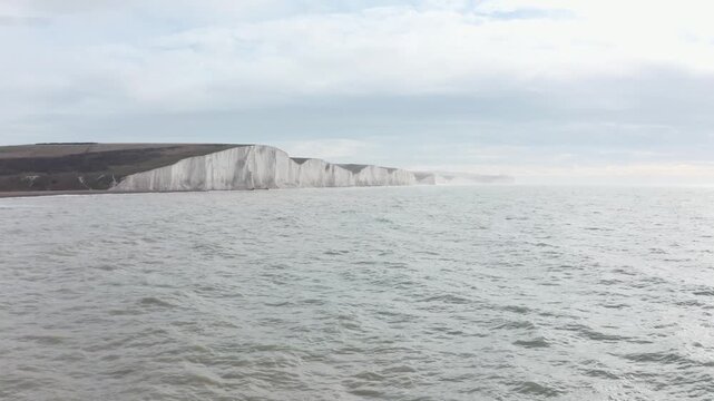 Aerial view of white chalk cliffs overlooking calm ocean water along southern england coastline.
