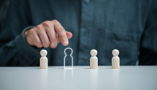 Man points toward wooden candidate figures, representing employee selection, recruitment, hiring decisions, applicant evaluation, talent management and workforce planning.